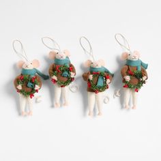 three ornaments shaped like mice with wreaths and bells on their backs, hanging from strings