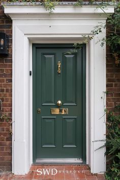 a green front door with brass handles on a brick building in london, england by swd architecture