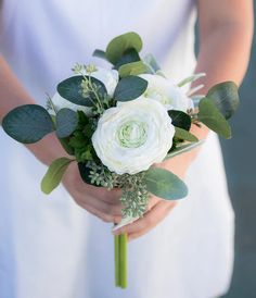 a woman holding a bouquet of white flowers