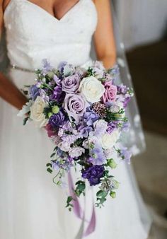 a bride holding a purple and white bouquet