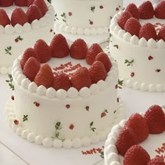 several cakes with white frosting and red strawberries on the top are arranged in rows