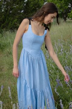 A truly special dress. With rich black ribbon tie straps, a corset bodice, and sweeping ruffle hem the Mirabelle Dress is dramatic, romantic beauty at its best and one of our most popular styles. Made in a lightweight blue gingham linen with a sateen finish that gives the linen a subtle dressy luster. A showstopper of a dress made for special moments, celebrations, or romantic getaways.