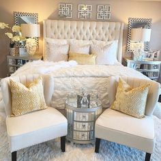 a white bed sitting in a bedroom next to two chairs and a table with lamps on it