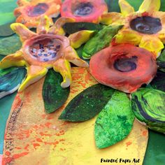 some flowers are sitting on top of a green plate with yellow and red paint all over it