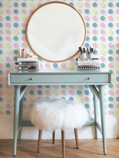 a blue desk with a round mirror above it