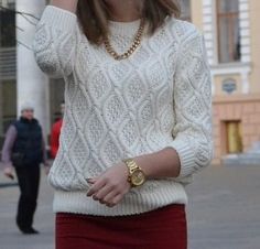 a woman is talking on her cell phone while walking down the street wearing a white sweater and red skirt