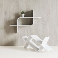 a white shelf with a plant in it next to a wall mounted shelving unit