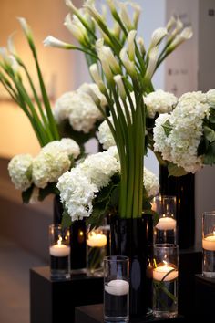 white flowers in black vases with candles