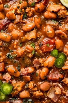 a bowl filled with beans and meat next to a lime slice on top of a table