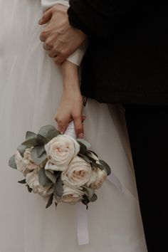 the bride and groom are holding each other's bouquets with white flowers on them