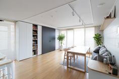 a living room filled with furniture next to a window covered in white blinds and wooden flooring