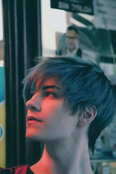 a woman with short hair standing in front of a bus looking off into the distance