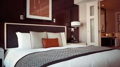 a bed with white and brown pillows in a bedroom next to a doorway that leads to another room