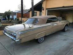 an old car parked in front of a garage