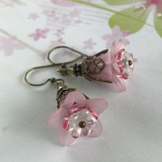 "Pretty in Pink... Add some spring to your wardrobe with these lovely double pink blossoms. Delicate pink petals surround bright pink and white centers. Antique brass filigree caps adorn the tops and a tiny green bead adds a bit of spring pop. These earrings are very lightweight and comfortable to wear. Perfect for a garden wedding, or a gift for a nature lover. And don't forget...Mother's Day is just around the corner. Drop length from bottom of antique brass french earwire: 1\" (25mm) Prefer a Feminine Pink Jewelry With Handmade Flowers, Pink Petal-shaped Earrings For Spring, Delicate Pink Flower Earrings For Spring, Pink Handmade Flower Earrings For Spring, Spring Pink Earrings With Handmade Flowers, Pink Earrings With Handmade Flowers For Spring, Pink Feminine Flower Drop Earrings, Feminine Pink Flower Drop Earrings, Pink Feminine Flower Earrings