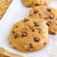 three chocolate chip cookies sitting on top of white paper