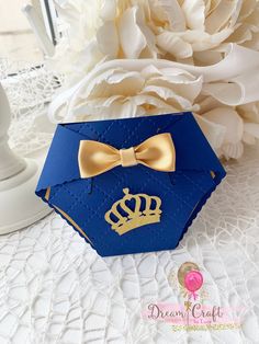 a blue box with a gold bow and a crown on it sitting next to white flowers