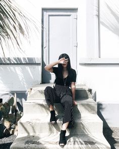 a woman sitting on the steps in front of a door with her hand up to her face