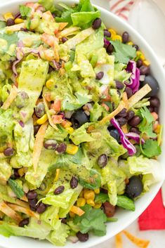 a salad with black beans, lettuce and avocado in a white bowl