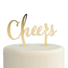 a white cake topped with a wooden cheers sign