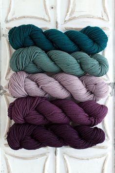 six skeins of yarn in various colors on a white background with an old door