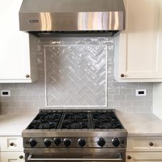 a stove top oven sitting inside of a kitchen next to white cabinets and cupboards