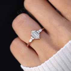 a woman's hand with an engagement ring on it, showing the center stone