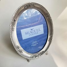 an oval silver frame with the seagull pewter logo on it is shown