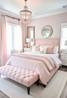 a bedroom with pink walls, white bedding and a chandelier hanging from the ceiling