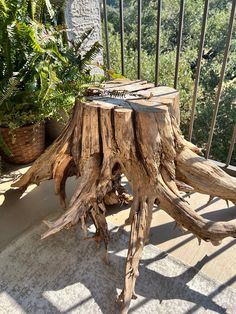 a wooden table sitting on top of a patio next to a potted green plant