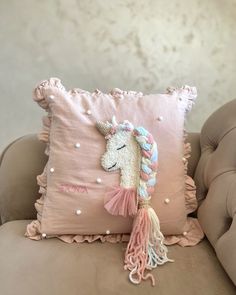 a pink pillow with a unicorn on it and tassels hanging from the back