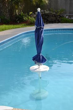 an umbrella is sitting in the middle of a pool