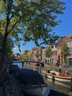 several boats are parked on the side of a canal in front of buildings and trees