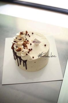 a cake with white frosting and chocolate sprinkles sitting on top of a piece of paper