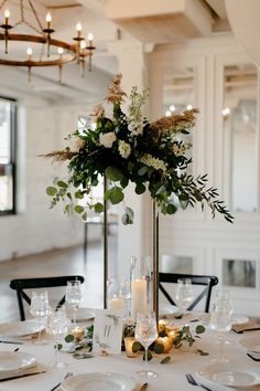 an elegant centerpiece with greenery and candles sits on a table in the dining room