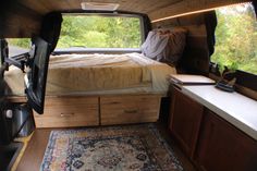 a bed in the back of a truck with an area rug on the floor next to it