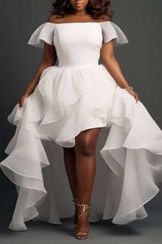 a woman wearing a white dress with ruffled skirt and high heels, posing for the camera