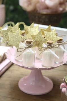 small bottles filled with marshmallows and gold stars on top of a cake plate