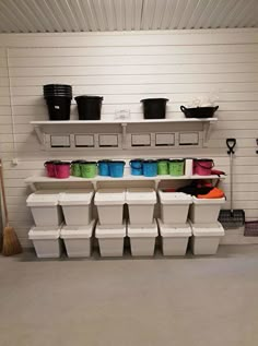 a garage with several storage bins and buckets on the wall next to each other