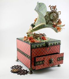 a decorative box with flowers and music notes on it's lid, sitting next to a clock