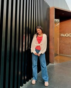 a woman standing in front of a building with her hands on her hips and looking at the camera