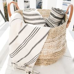 a basket filled with towels on top of a white table next to a window sill