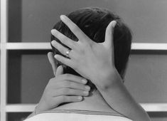 a woman with her hand on her head and hands behind her back, in black and white