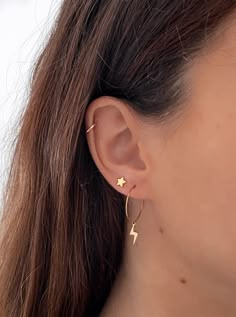 a woman wearing a pair of earrings with lightning bolt on the back of her ear