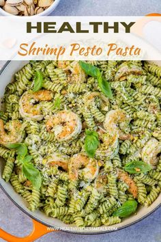 shrimp pesto pasta in a skillet with basil leaves and sunflower seeds