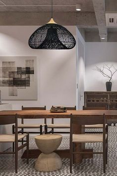 a dining room table and chairs in front of an art work hanging from the ceiling