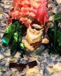 a small figurine sitting on top of a pile of fake flowers and leaves