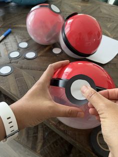 a person holding a poke ball in front of some other items on a wooden table