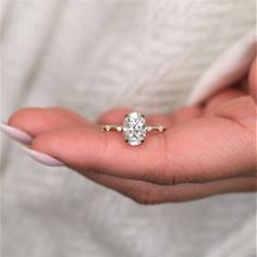 a woman's hand holding an engagement ring in her left hand, with the diamond on it