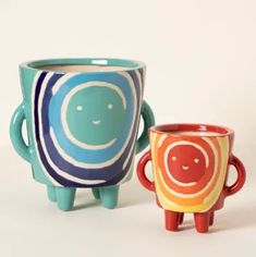 two colorful cups with faces on them sitting next to each other